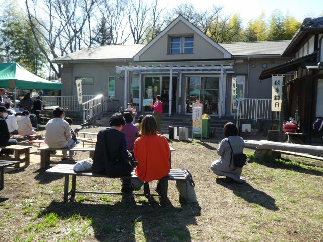 画像：中庭でベンチに座っておはなし会を聞いている様子の写真