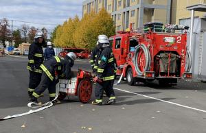 画像：ホースカーでホースを延長して消防ポンプ車に中継している様子の写真