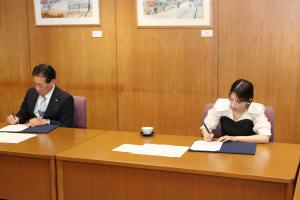 画像：署名を交わす二瓶有加さんと河村孝市長の写真（拡大画像へのリンク）