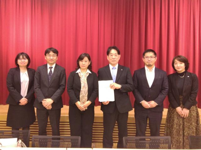 画像：委員の皆さんと市長が報告書を手に記念の写真