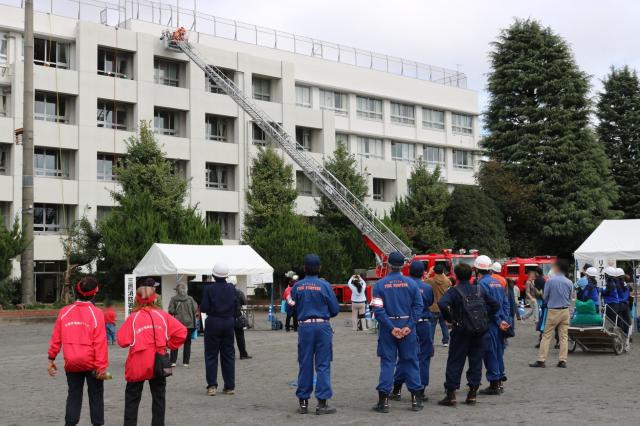 画像：はしご車のはしごを校舎屋上まで伸ばして要救助者を救助する様子