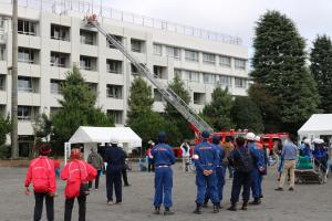画像：はしご車のはしごを校舎屋上まで伸ばして要救助者を救助する様子（拡大画像へのリンク）