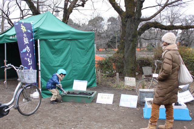 画像：バットに入れて展示している池底の土をかき混ぜる男の子の様子