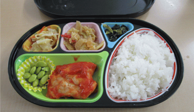 画像：お食事例。ごはん、主菜（鶏肉）、副菜（和え物）、漬物など。
