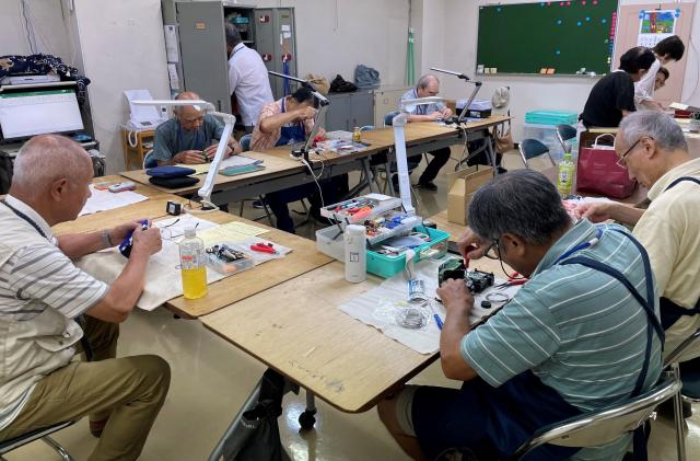 画像：写真：おもちゃを直す会員の皆さんの様子